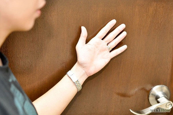 Cảm nhận sức nóng của cánh cửa bằng mu bàn tay. Cách Thoát Thân An Toàn Khi Xảy Ra Hỏa Hoạn